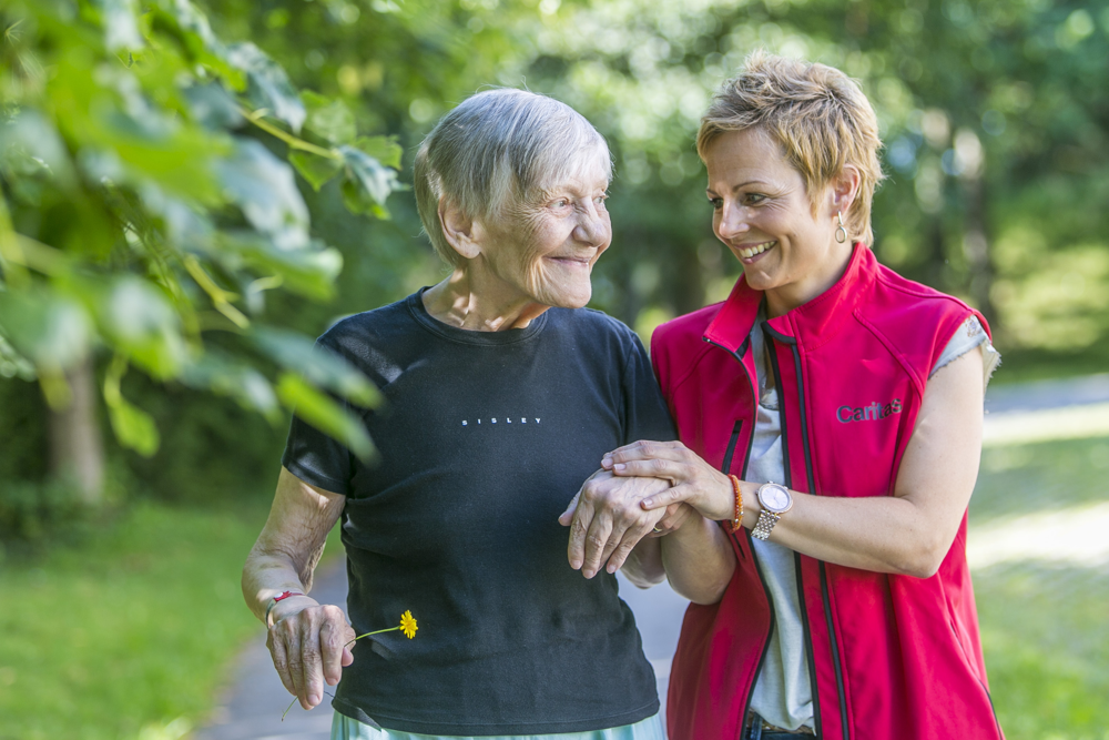 A Personal Support Worker shares a laugh with a senior during a walk.